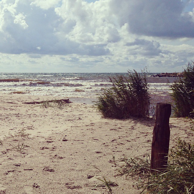 Boderne strand med sandstrand i forgrunden og havet længere væk og skyet himmel