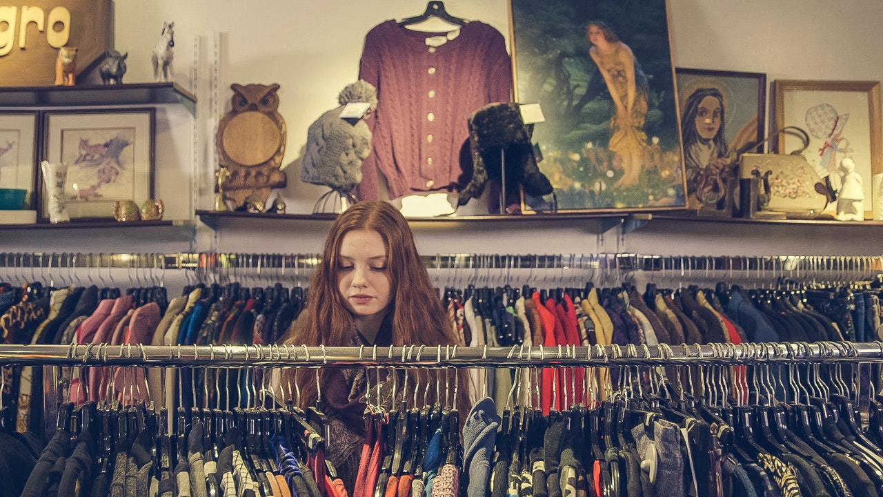 En ung pige kigger på tøj i en genbrugsbutik
