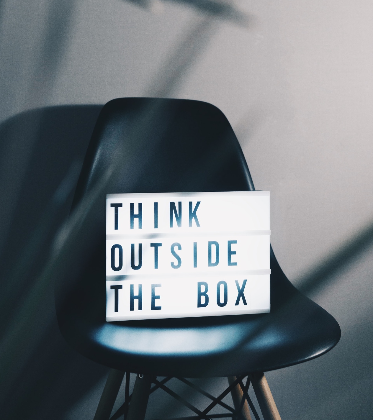 I en sort stol står der en lysende boks med teksten "Think outside the box"